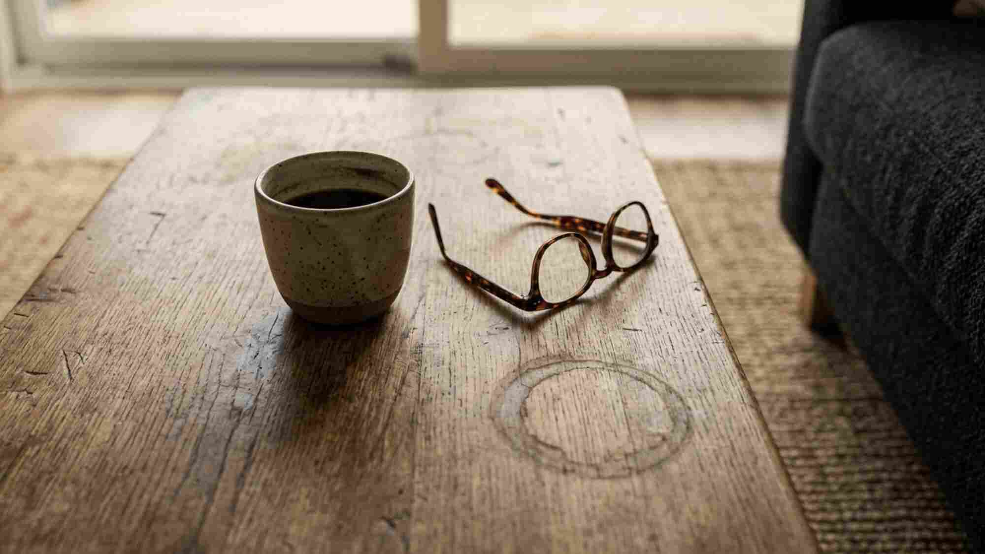 Close up of a worn second-hand solid oak coffee table with patina on a jute rug in a small Japandi living room