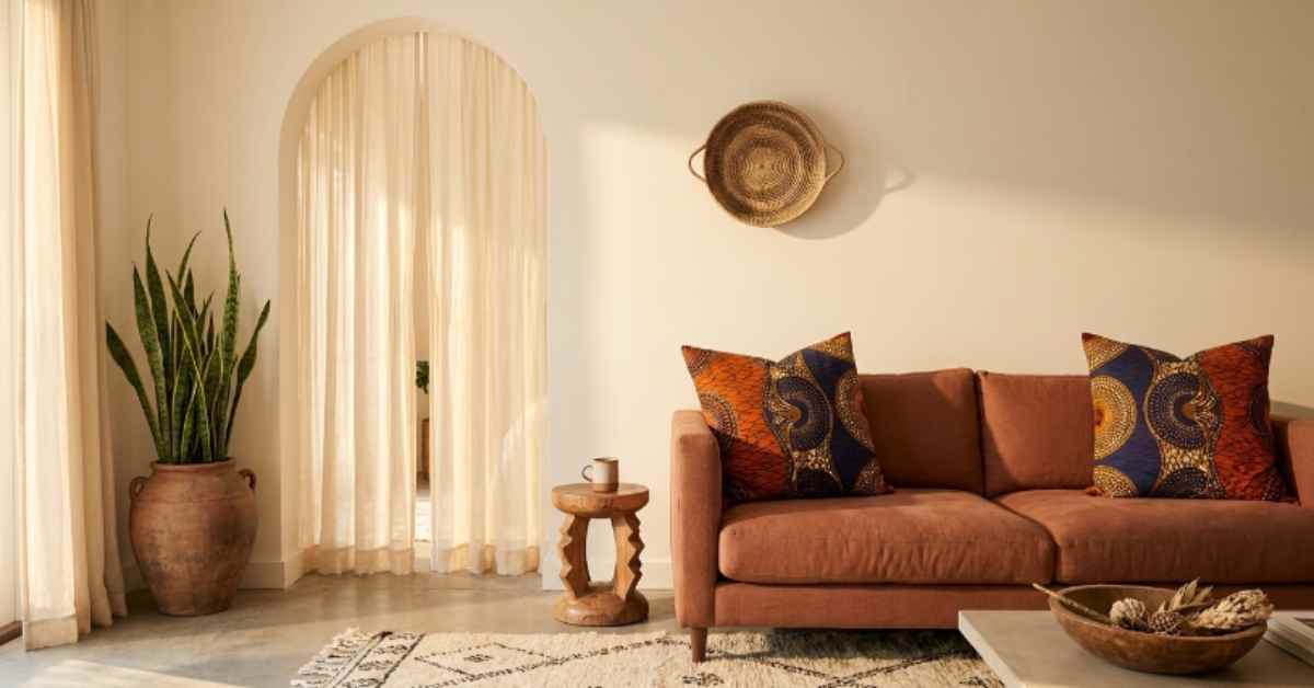 Warm Afrohemian living room with a terracotta linen sofa, Ankara throw pillows, hand-knotted Berber rug, snake plant in clay pot, and woven basket wall decor in soft afternoon light