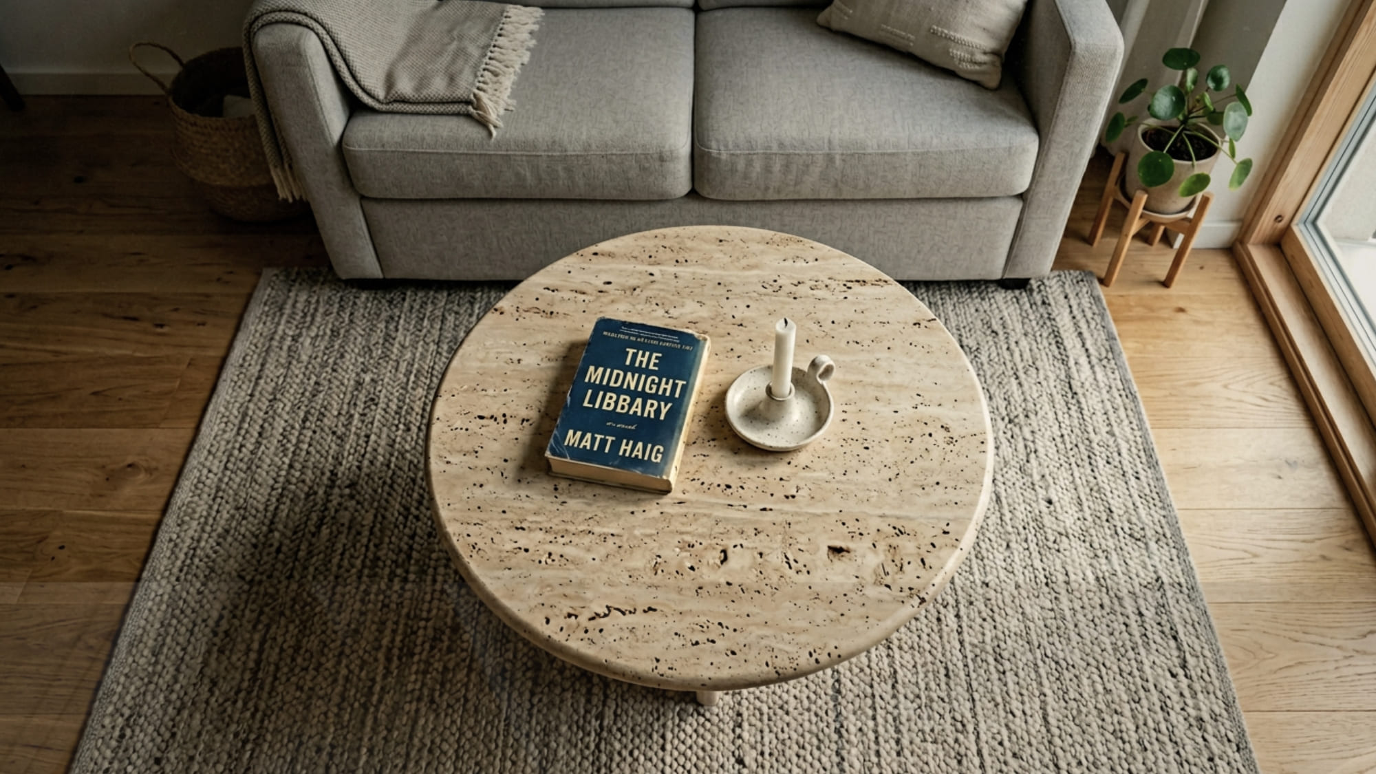 Round travertine coffee table in a small living room with walkable space around all sides and a sofa behind it